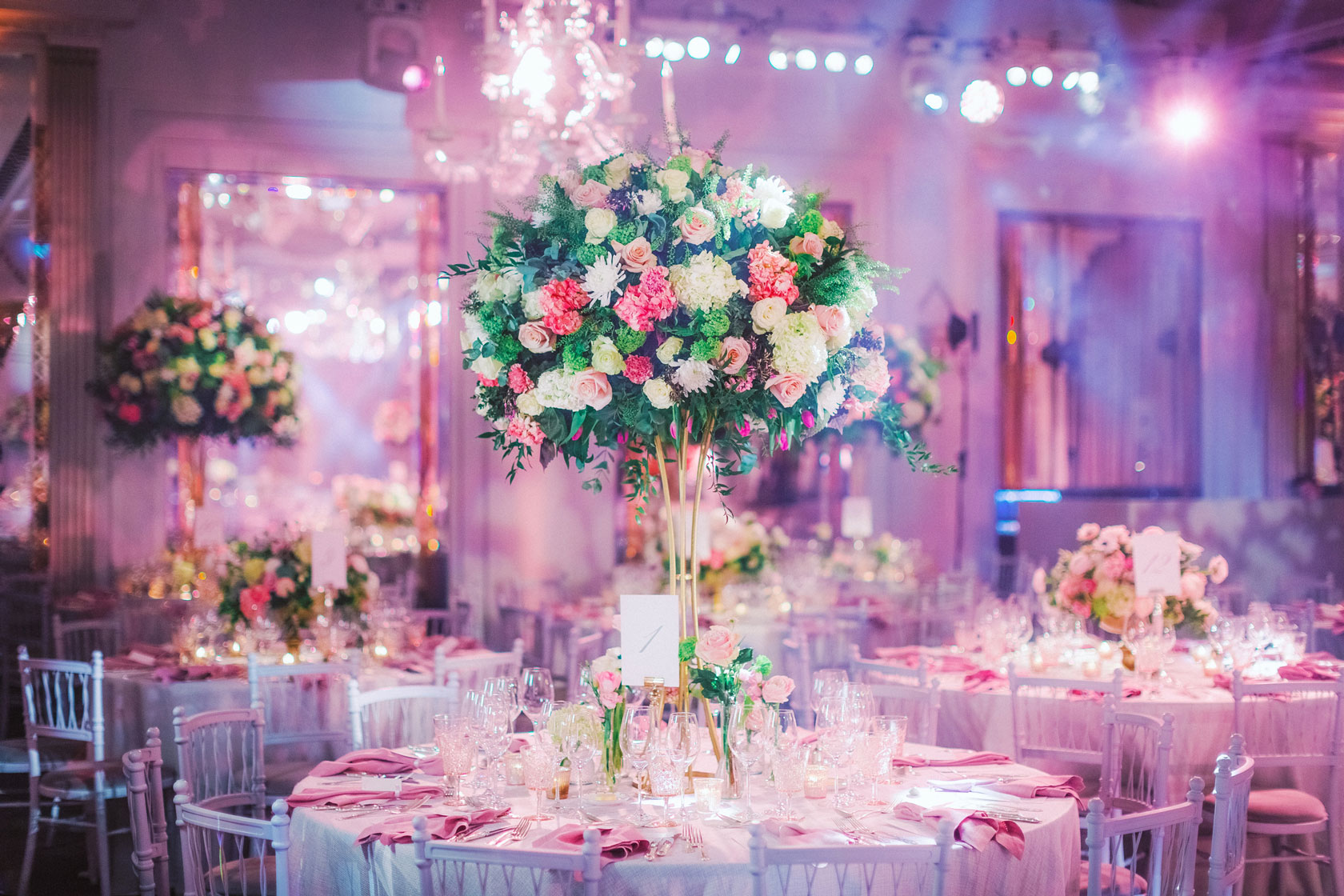 large floral arrangment on table top for wedding with chairs and mood lighting in Claridges Ballroom